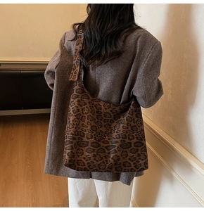 Detailed view of a large leopard print suede tote bag worn over a brown wool coat
