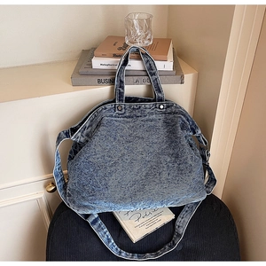 Close-up of retro acid wash denim tote bag with metal rivets on a black chair