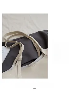 Detailed close-up of ivory pebble leather tote strap and silver metal buckle hardware