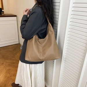 Detail view of large caramel hobo bag with litchi texture on a model shoulder