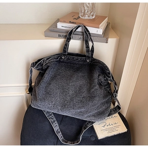 Detailed view of the dark grey denim tote bag with washed texture and metal hardware