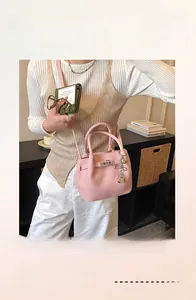 Détail du sac seau en cuir litchi rose avec boucle en métal et breloque en cœur
