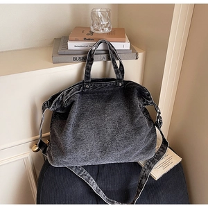 Close-up of washed denim tote bag showing metal rivet details and adjustable strap
