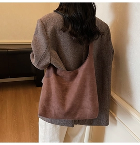 Detail of vintage brown suede tote bag showing texture and slouchy fit on model shoulder