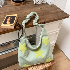 Detail of mint green shoulder bag featuring yellow star patches and ruffled strap design