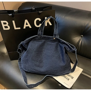 Detail of dark blue denim tote bag with visible stitching and metal rivet accents