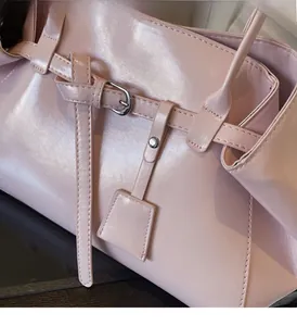 Detail of pink vintage underarm bag with leather strap buckle and matching square pendant