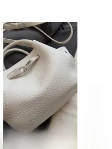 Detailed close-up of white lychee leather texture and silver metal twist lock closure