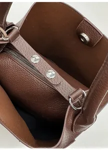 Gros plan de l'intérieur du sac en cuir marron avec poche zippée et fermoir magnétique