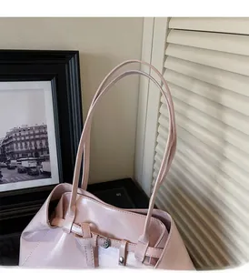 Detail view of long slender pink shoulder bag handles and silver metal buckle hardware