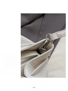 Close-up of silver metal hook and refined stitching on a white litchi pattern bucket bag