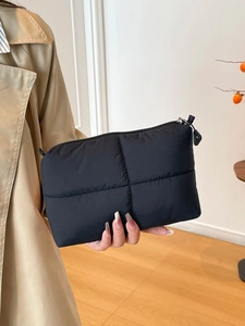 Bolso de mano acolchado negro minimalista con textura esponjosa y cremallera