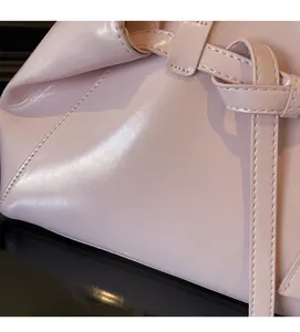 Close-up of glossy pink leather shoulder bag featuring refined stitching and soft texture