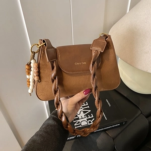 Détail de la texture suède mate avec bandoulière en cuir tressé et breloque perlée