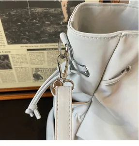 Detail of durable silver metal swivel hook and drawstring on a grey faux leather tote bag