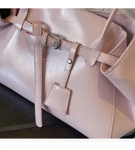 Detail of light pink faux leather handbag with silver buckles and elegant stitching