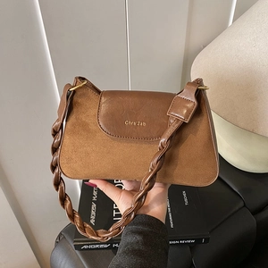 Détail du sac bandoulière marron mat avec bandoulière tressée et logo doré élégant