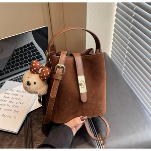 Détail du sac seau vintage en daim mat avec fermoir doré et breloque ours en peluche