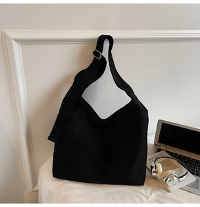 Detail of wide shoulder strap with golden metal buckle on black canvas tote bag