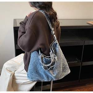 Model wearing a large light blue washed denim shoulder bag for daily casual commute use