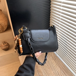 Détail du sac bandoulière noir avec poignée tissée et perles de bois colorées