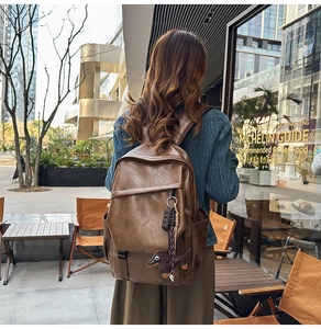 Close-up of brown faux leather backpack with front zipper pocket and dog keychain