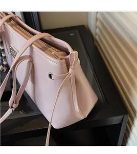 Close-up of pink leather tote bag with side bow tie and silver metal eyelet detail