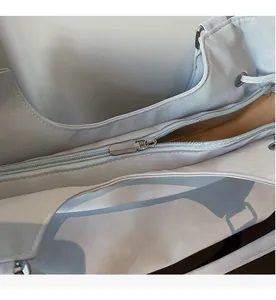 Detail view of smooth silver metal zipper and large opening on light blue faux leather bag