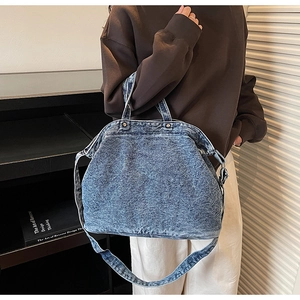 Close-up of washed blue denim tote bag featuring vintage metal rivets and stitching