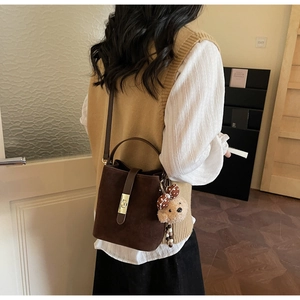 Détail du sac seau vintage marron avec fermoir doré et pendentif ourson en peluche