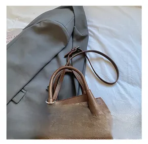 Detail der braunen Litschi-Lederstruktur und des Metalldrehverschlusses der Beuteltasche