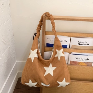 Detail of caramel suede hobo bag with white plush stars and scrunchie shoulder strap
