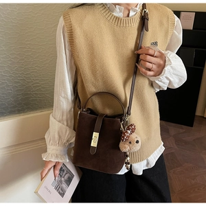 Détail du sac seau vintage en daim marron avec breloque ours et fermoir tournant doré