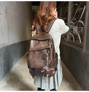 Brown vintage leather backpack featuring a cute dog pendant and multi-pocket design