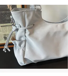Close-up of light blue leather tote bag showing soft texture, side pocket and drawstring detail