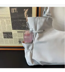 Detail of light blue leather tote bag showing side drawstring pocket with skincare bottle