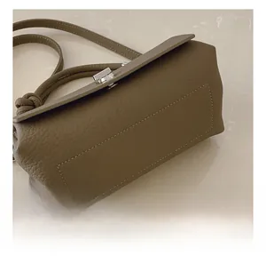 Close-up of deep olive green pebbled leather bag featuring precise stitching and metal lock