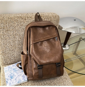 Detail of vintage brown PU leather backpack with buckle closure on a modern sofa