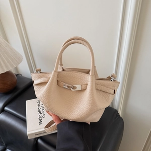 Gros plan du sac seau en cuir beige avec motif litchi, fermoir doré et poignée élégante