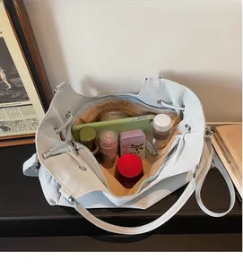 Macro view of the large interior space of this blue tote bag holding cosmetics and phone