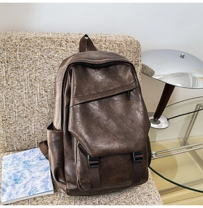 Detail shot of vintage coffee faux leather backpack with buckles on a white chair
