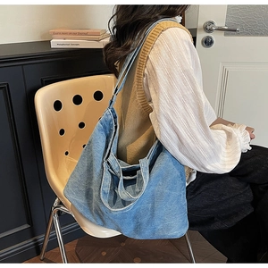 Detail of blue denim tote bag with visible white stitching and large capacity