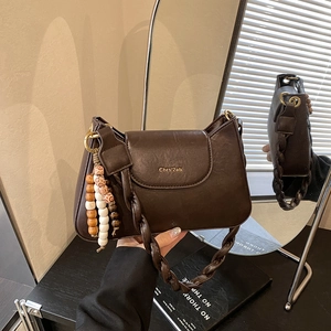 Détail du sac marron vintage avec poignée tressée et perles décoratives en bois colorées