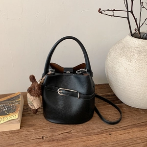 Détail d'un sac seau en cuir grainé noir avec boucle argentée et breloque ours sur bois