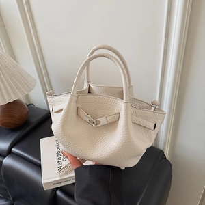 Détail du sac seau crème montrant la texture du cuir grainé et la boucle métallique
