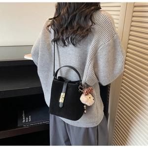 Détail du sac seau noir mat avec fermoir doré et pendentif peluche ours mignon et stylé