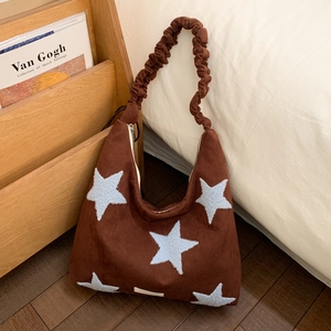 Detail of soft dark brown suede hobo bag with blue star pattern and scrunchie strap