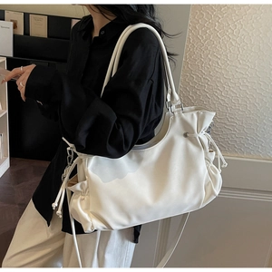 Close-up of a large white PU leather tote bag with drawstring sides on a model