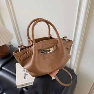 Détail d'un sac seau marron à motif litchi avec boucle en métal et doubles poignées