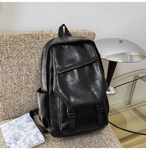 Close-up of black leather backpack with metal buckle on a cozy modern sofa